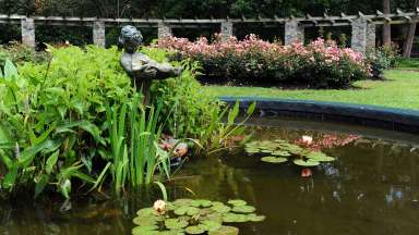 Statue in a small fountain in front of an arbor at the Raleigh Rose Garden