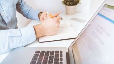 image of man writing next a lap top