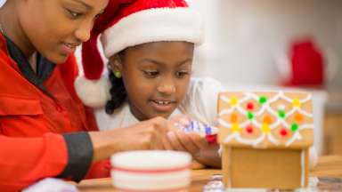 Mom and daughter decorating gingerbread house