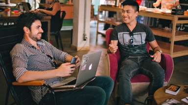 Two young men chatting while sitting casually indoors