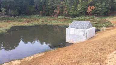 A concrete dam structure that carries water under Laurel Hills Road