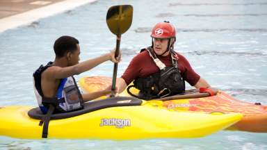 An instructor and student in the pool working on kayak basics