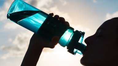 Woman drinking from water bottle in the sun