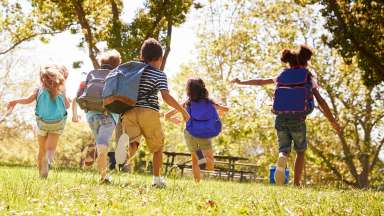 Group of schoolchildren running in a field, back view