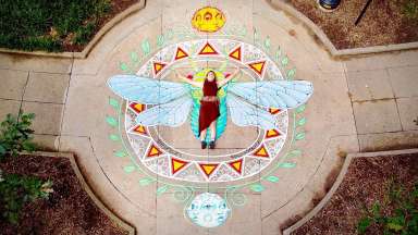 The artist lays on her mural of a cicada in Nash Square