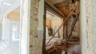 Man on ladder repairing interior of a building