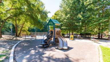 Eastgate Park with playground equipment in foreground and tennis and basketball courts in background