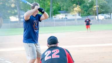 Man up to bat on a baseball field with catcher behind the base. 