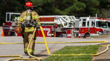 Raleigh firefighter pulling fire hose into road