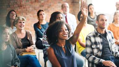 Young lady raising hand in group setting