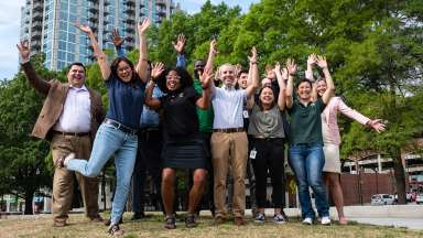 City staff jumping on grass at park