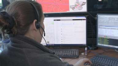 Woman taking calls at call center in front of computer screens