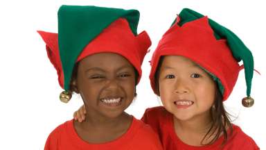 two children smiling with holiday elf hats on