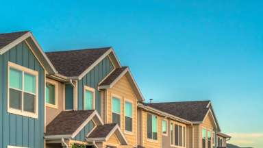 blue sky with top level of a row of townhomes visible