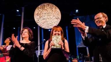 People standing on stage and clapping at the 2022 Raleigh Medal of Arts Awards