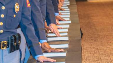 police officers in uniform with hands on swearing in book