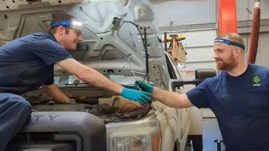 Two staff members working on a City of Raleigh vehicle