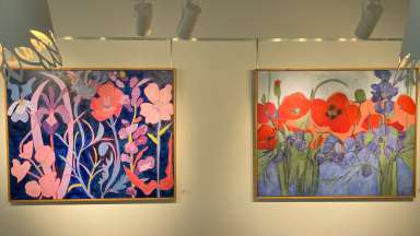 Two colorful floral paintings hung in a gallery