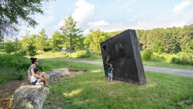 Image of a large concrete monolith sculpture with information about stormwater infrastructure printed on it.