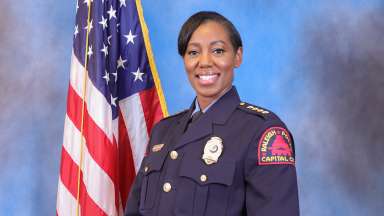 Chief Patterson in uniform standing by an American flag