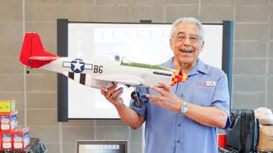 a smiling instructor hold a model airplane