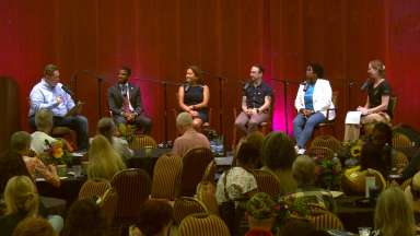 Six individuals sit on stage in line. Two of them are City of Raleigh staff and three are community leaders.