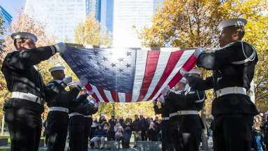 Military personnel hold American flag at the grounds of the previous World Trade Center