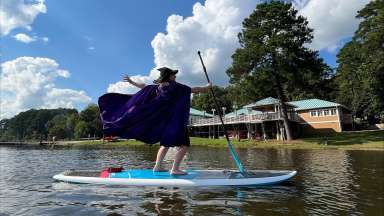 a person dressed up as a witch on a paddle board