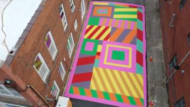 aerial photograph of a coilorful street mural and a brick building