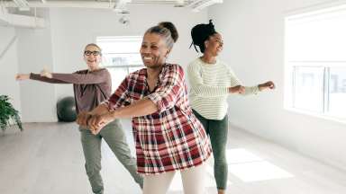 three people smiling and dancing in a workout studio