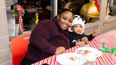 an adult and child smiling while decorating holiday cookies