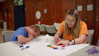 an image of an intern coloring with markers with a camper