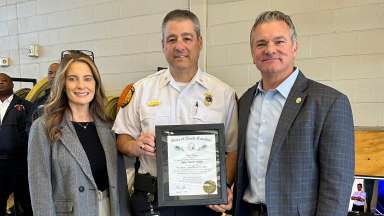 Fire chief holding a framed award at ceremony