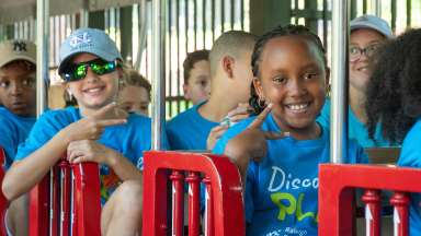 summer camp children smiling on the Pullen park train