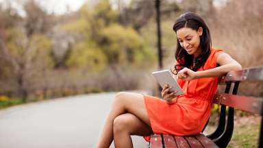 Woman sitting on a park bench scrolling on a mobile device