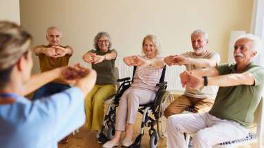 a group of people doing wrist rolls while sitting in wheelchairs