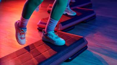 sportsperson exercising on step platform at gym with other people training