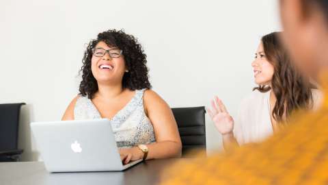 woman laughing at a desk with a laptop