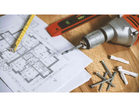 Image of plans, pencil, level, drill, and screws laying on a table