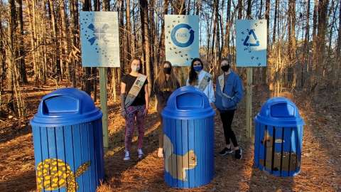 Girls standing with painted trash cans