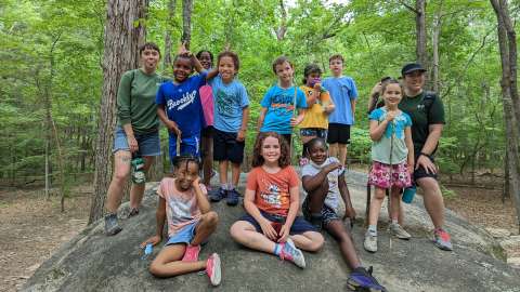 summer campers sitting on large rock