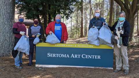 a group of volunteers wearing masks, and holding trash bags