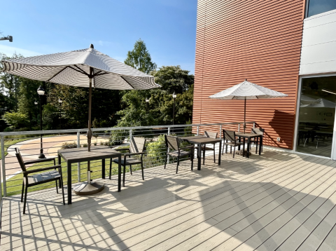 Deck with three tables, two outdoor umbrellas, and six chairs.