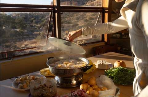 photograph of a person working with food in front of a window.