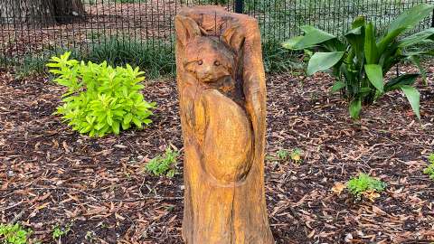 A wood stump with the face and tail of a fox carved into in.