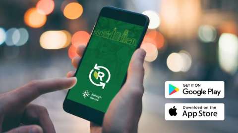 A person holds a smartphone showing the Raleigh Reuse app. 