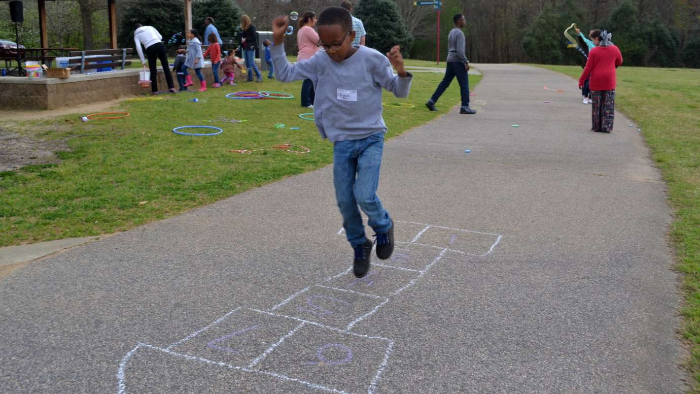 Young boy playing hopscotch on pavement at Anderson Point Park