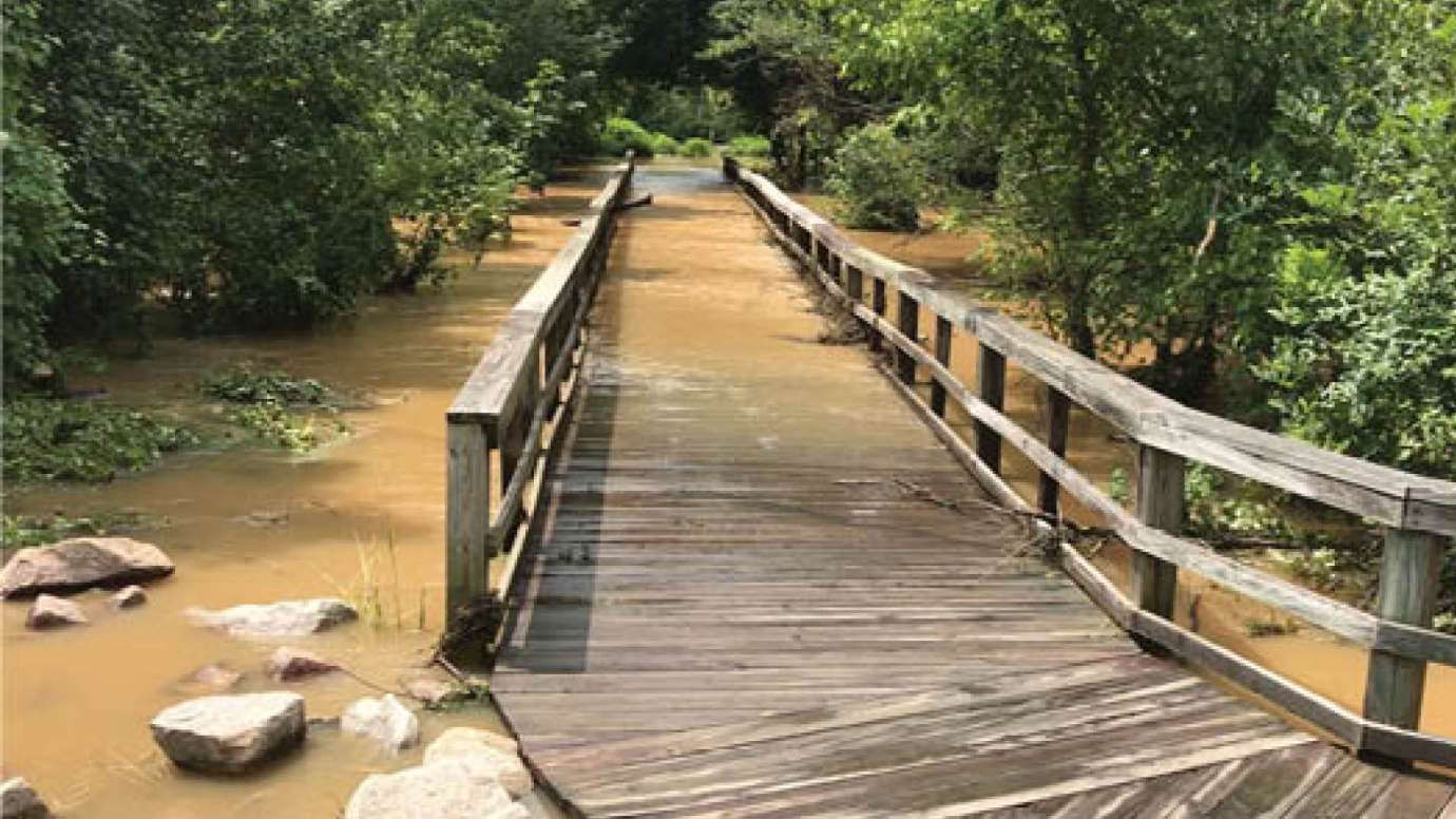 A creek flooding the greenway bridge on Rose Lane