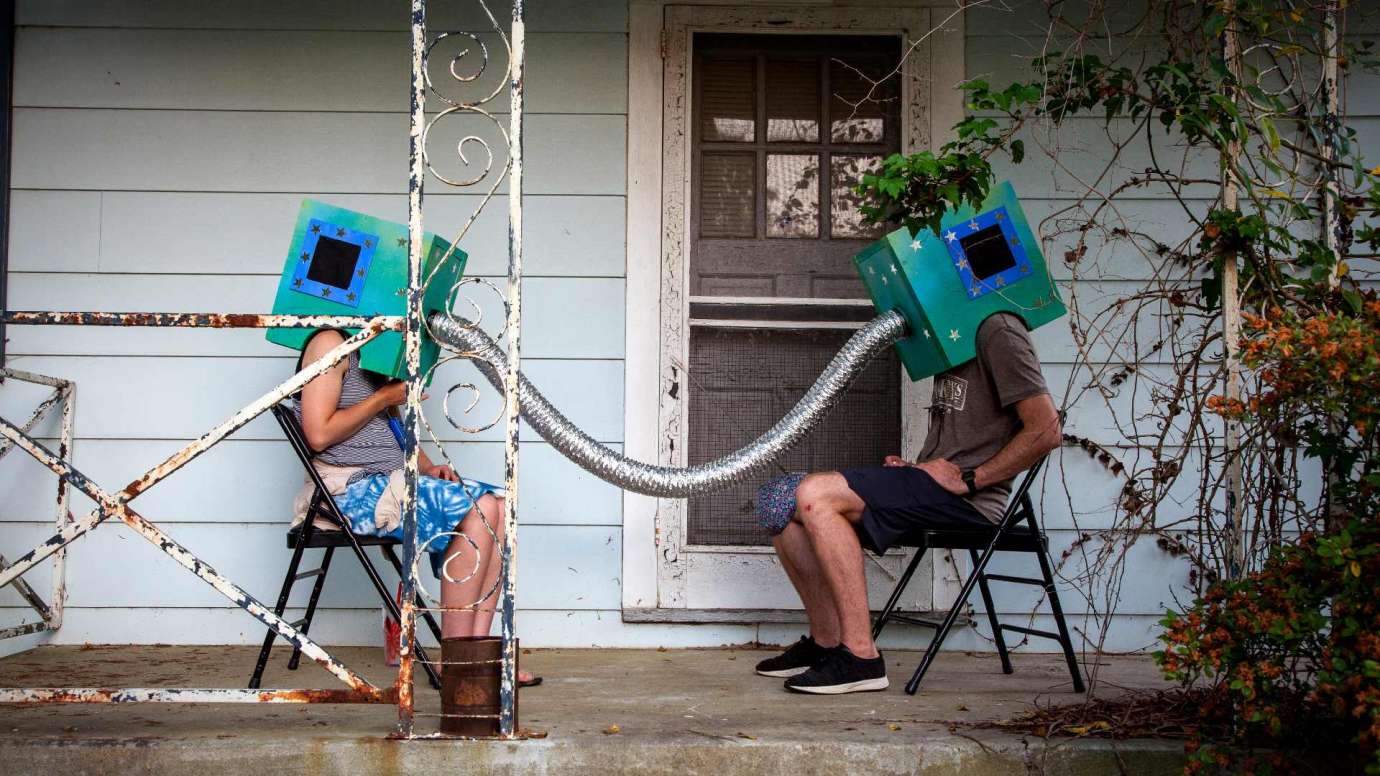 An interactive art installation, two people with boxes on their heads connected by a metal tube