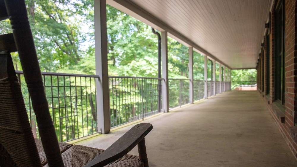 View of large balcony over looking trees with rocking chair in right forefront